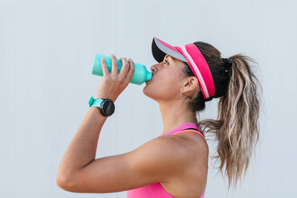 Girl drinking water after training. - Foto, afbeelding