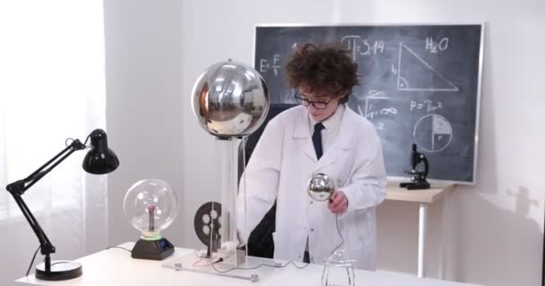 教育、科学、子供の概念-少年は電気テストを行う物理学研究室のためのゴーグルを着用。研究室で電気放電を勉強する子供. - 映像、動画