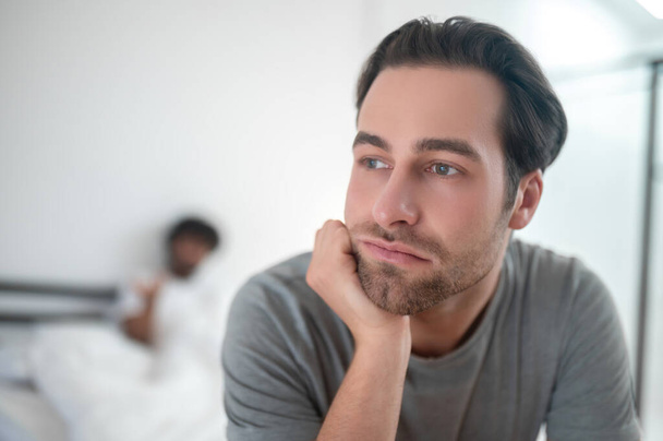 Despondent young man sitting in the bedroom - Foto, Imagen