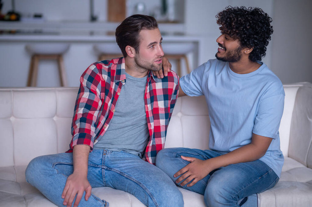 Biracial gay couple having a conversation on the sofa - Photo, Image
