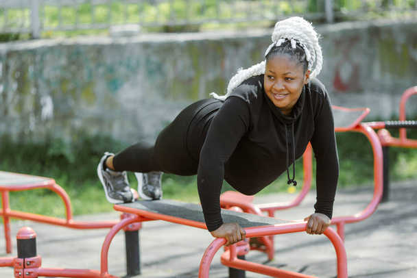 Afro-american plus size woman doing workout exercises session outdoor - Photo, Image