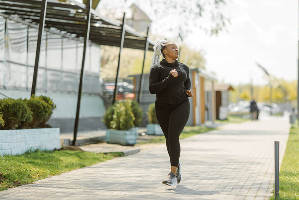 Afro-american plus size woman jogging outdoor - Фото, изображение