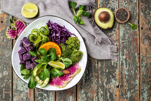 veganský salát se sladkými brambory, brokolicí, avokádem, fialovým zelím, okurkou, ředkví a mandlemi. Čisté stravování, dietní stravování. pohled shora. - Fotografie, Obrázek