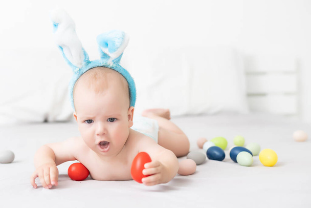 Portret van een schattige baby gekleed in paashaas oren met een mand vol eieren - Foto, afbeelding