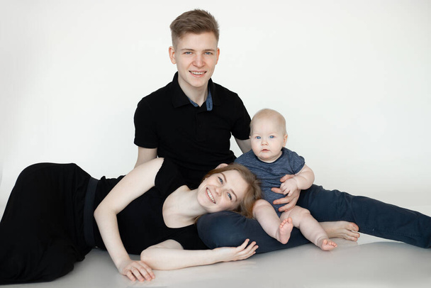 Happy smiling family standing together in studio, threesome in black clothes. Planning traveling and vacation, holidays. - Valokuva, kuva