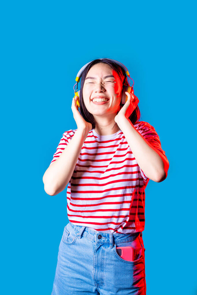 Mladý asijské žena izolovaný pozadí poslech hudba bezdrátové sluchátka smích - Fotografie, Obrázek