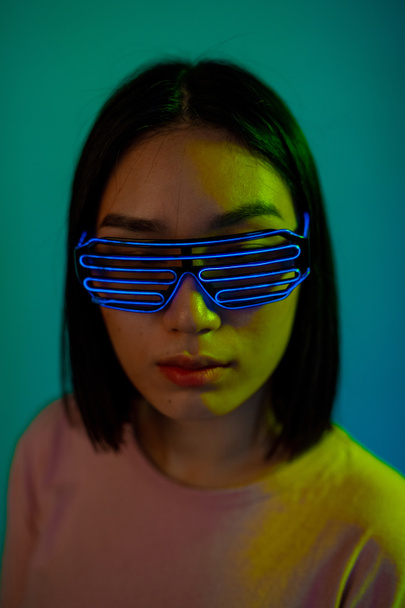 Молодая женщина, одетая в футуристические метафоры, привела очки на голубом фоне изолированы - Фото, изображение