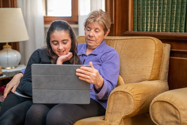 Kislány ellazul néz tabletta a nappaliban a nagymamával - Fotó, kép