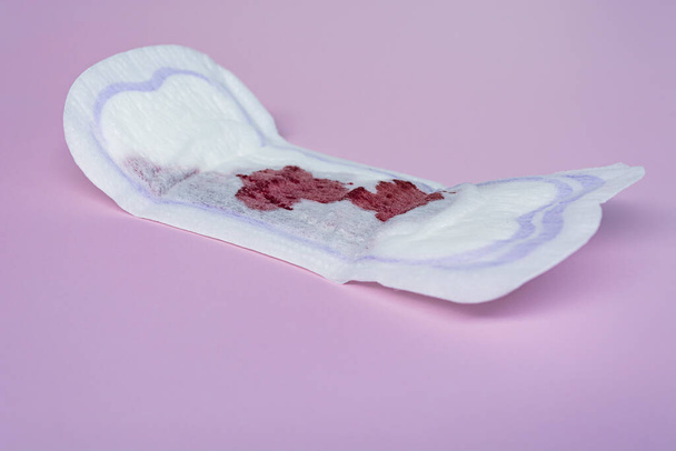 Менструальная кровь на гигиенической подушке на розовом фоне. Женская гигиеническая защита. Принято. Плоский лежал. - Фото, изображение