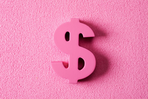 closeup of a pink dollar sign on a textured pink background, depicting the pink money or pink capitalism concepts - Valokuva, kuva