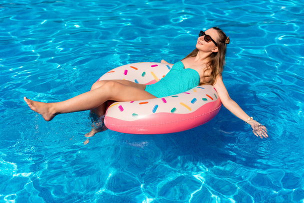 jeune femme en bikini nage sur le beignet d'eau gonflable dans la piscine - Photo, image