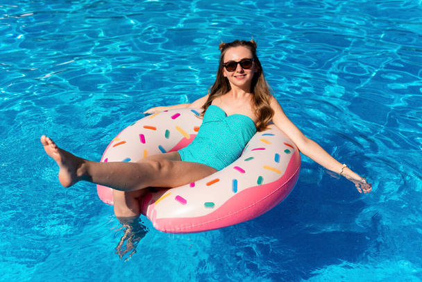 mujer joven en bikini nada en la rosquilla inflable de agua en la piscina - Foto, imagen