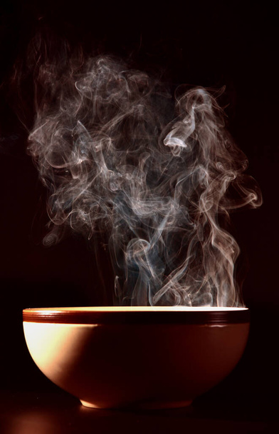 カップの上の食べ物から立ち上がる煙の写真熱い食べ物の概念. - 写真・画像