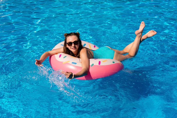jovem mulher de biquíni nada no donut de água inflável na piscina - Foto, Imagem