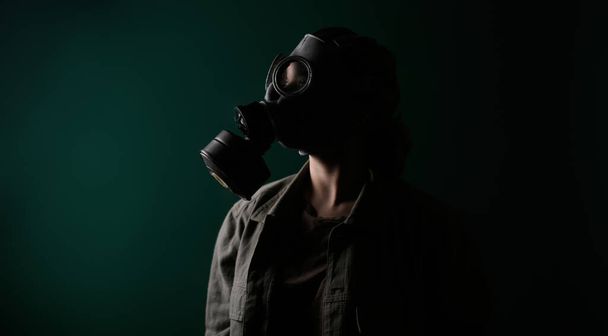 Photo of a military man in a gas mask, apocalypse, nuclear weapons, atomic explosion of a station, chemical and nuclear weapons protection. Girl in a mask on a green background, war - Photo, Image