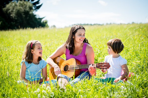 Mother playing guitar in nature to children - Zdjęcie, obraz