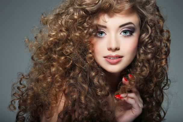 Young beautiful woman with long curly hairs - 写真・画像