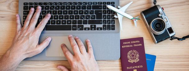 Baner poziomy lub nagłówek z męskich rąk wpisując na nowoczesnym laptopie do rezerwacji lotu samolotem - Człowiek planuje wycieczkę para z paszportami na biurku na wakacje - Różne paszporty narodowości - Zdjęcie, obraz