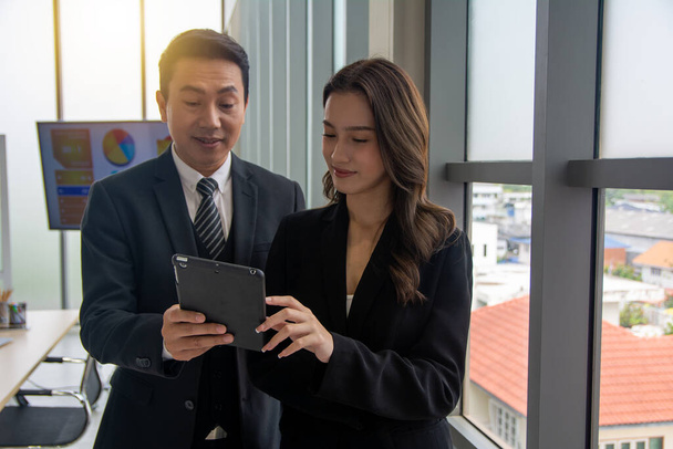 Businessman manager having discussion with businesswoman meeting in office meeting room. Two diverse professionals talking using tablet discussing project strategy, checking corporate plan. - Photo, Image