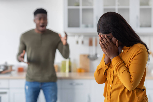 Психологическое насилие. Чёрная молодая женщина закрывает лицо, пока её парень кричит на неё - Фото, изображение