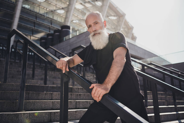 Portrait of attractive virile sportive healthy grey-haired man sportsperson standing on stairs fresh air spending time outdoors - Foto, imagen