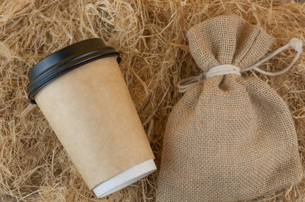 taza de café desechable de café con bolsa sobre fondo de paja. Vista superior - Foto, imagen