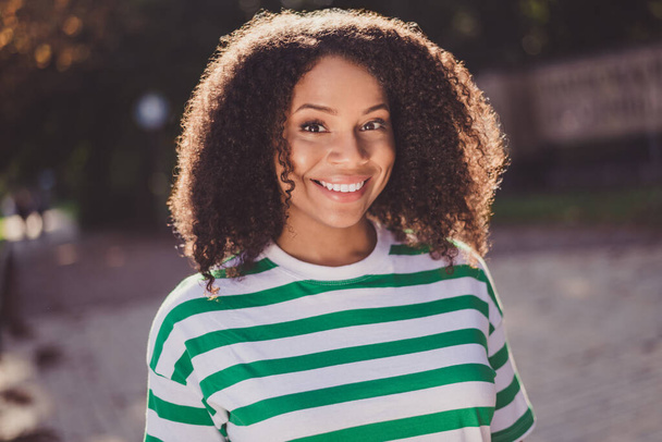 Photo of young lovely african woman glad enjoy journey trip abroad spend weekend wear striped t-shirt outdoors - Foto, afbeelding