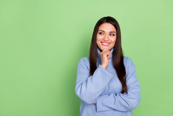 Photo of thoughtful pretty young woman wear blue sweater smiling looking empty space arm chin isolated green color background - Foto, Imagen