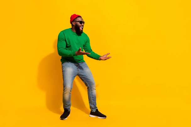 Photo of funny nice dancer man enjoy disco wear sunglass red beanie green shirt isolated yellow color background - Foto, Imagem
