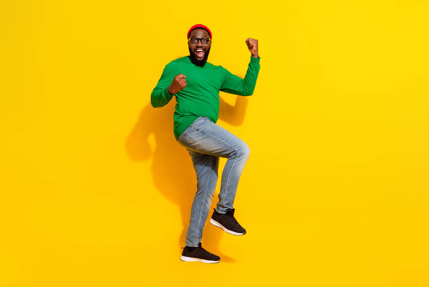 Photo of glad successful man celebrate victory wear specs red beanie green shirt isolated yellow color background - Foto, immagini