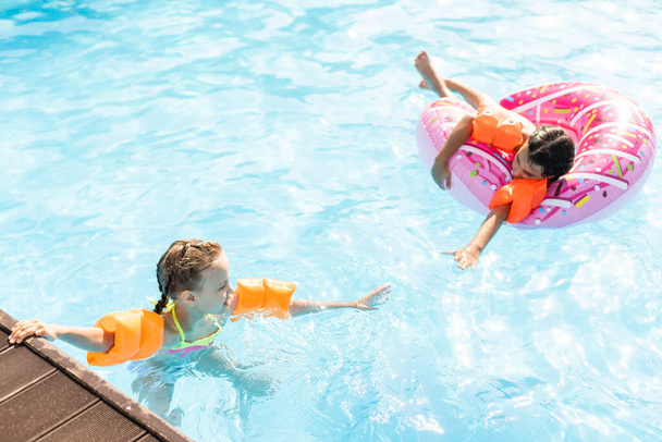 Счастливые дети в бассейне. Забавные дети играют на свежем воздухе. Летние каникулы. - Фото, изображение