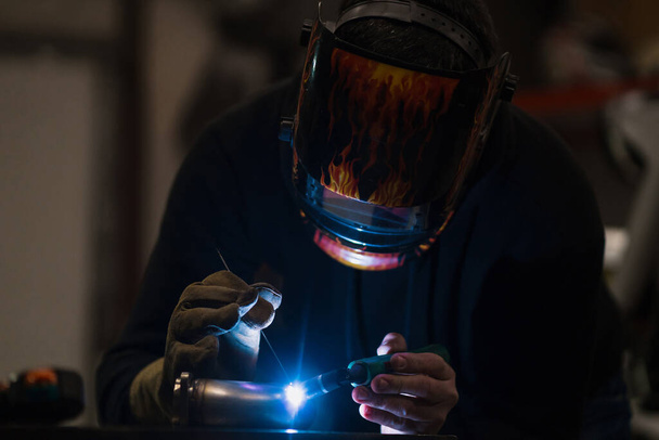Man working with argon welding machine in a garage - Foto, Imagen