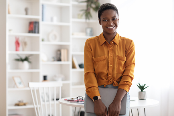 Mujer afroamericana bastante posando con portátil en la oficina - Foto, Imagen