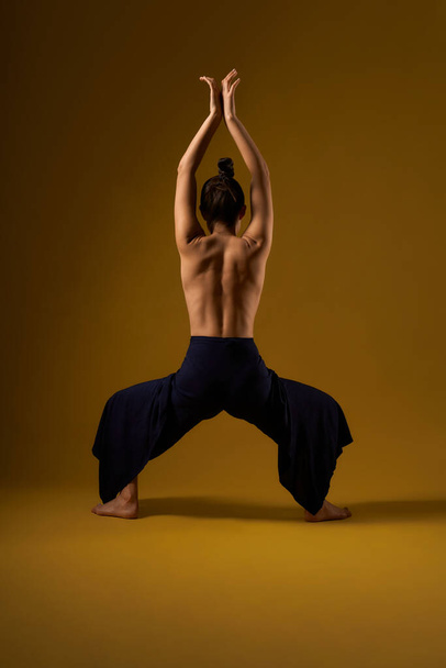 Girl with bare back practicing yoga at studio. - 写真・画像