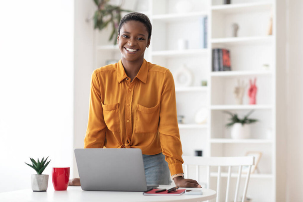 Θετική Αφροαμερικανή με κοντά μαλλιά που ποζάρει στο γραφείο - Φωτογραφία, εικόνα