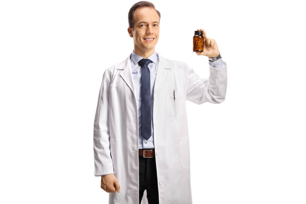 Male doctor showing a bottle of pills and looking at camera isolated on white background - Photo, Image