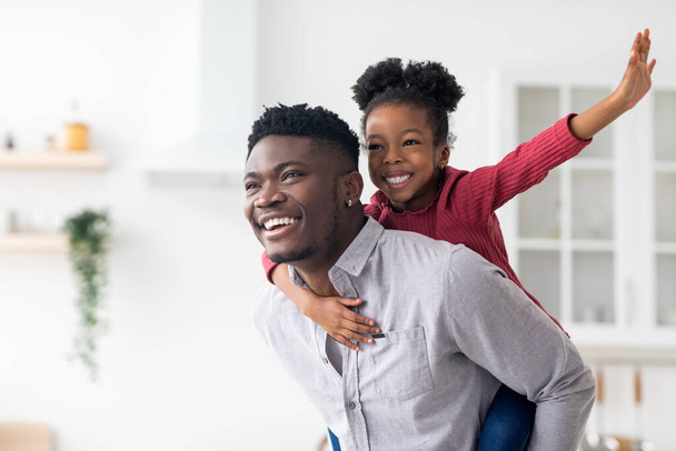Happy black father piggybacking his pretty little daughter - Photo, Image
