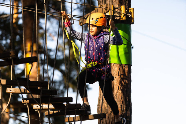 adventure climbing high wire park - people on course in mountain helmet and safety equipment - Foto, Imagem