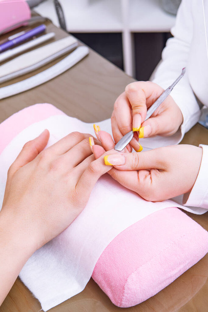 Manicurist preparing clients fingernail cuticles in salon - Foto, Imagem