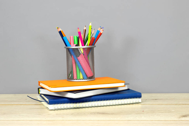 Terug naar school concept - schoolbord met potlood-doos en boeken, notebook en klok op houten tafel. - Foto, afbeelding