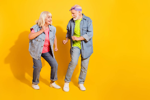 Photo of funny charming girlfriend boyfriend dressed denim outfit dancing empty space isolated yellow color background - Fotoğraf, Görsel