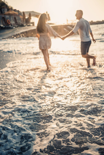 Summer holidays and travel. Sexy woman and man in sea water at sunset. Loving couple relax on the sunrise beach. Love relationship of a couple enjoying a summer day together - Foto, Bild
