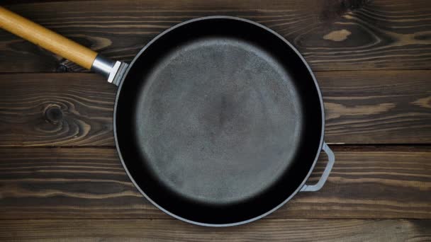 An empty cast iron skillet on a wooden table. Frying pan ready for cooking. Copy space for text and adv. Blank Space. Copy and Paste. Template for restaurant. Empty space for advertising. Top view - Footage, Video