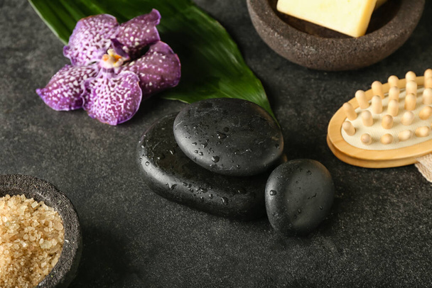 Piedras de spa húmedas con sal marina y cepillo de masaje sobre fondo oscuro - Foto, imagen