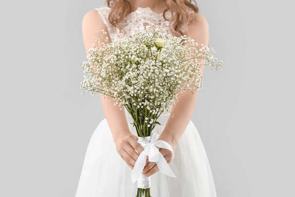 Schöne Braut mit Blumenstrauß auf hellem Hintergrund - Foto, Bild