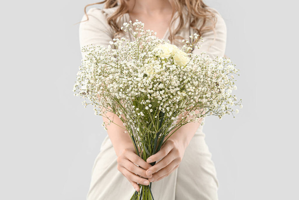 Красивая молодая женщина с букетом цветов на светлом фоне - Фото, изображение