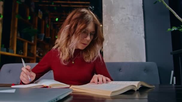 Eine junge, traurige Studentin, mit Hausaufgaben überfordert, sitzt mit einem Laptop in einem Café. - Filmmaterial, Video