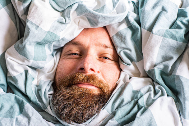 Ευτυχισμένος χαλαρός άνθρωπος πορτρέτο κοιμάται σε πάπλωμα - Φωτογραφία, εικόνα