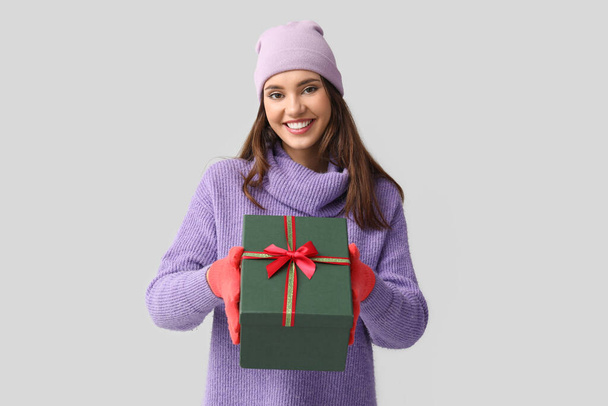 Young woman in red gloves with gift box on light background - Photo, image