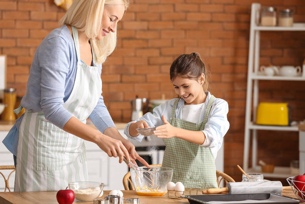 Klein meisje en haar grootmoeder bereiden deeg voor koekjes in de keuken - Foto, afbeelding